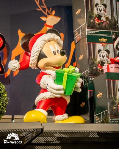 Mickey Mouse en figurine de Noël tenant un cadeau chez Tournesols.